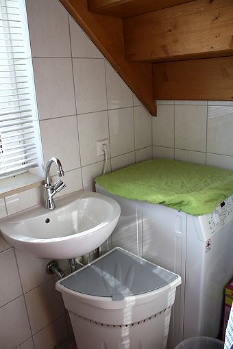 Das Gäste-WC der Ferienwohnung: Toilette, Waschbecken und Waschmaschine im EG